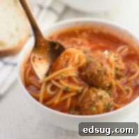 spaghetti and meatball soup in a bowl with a spoon