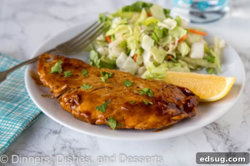 A plate of lemon turkey cutlet on a plate with lemon wedge and herbs