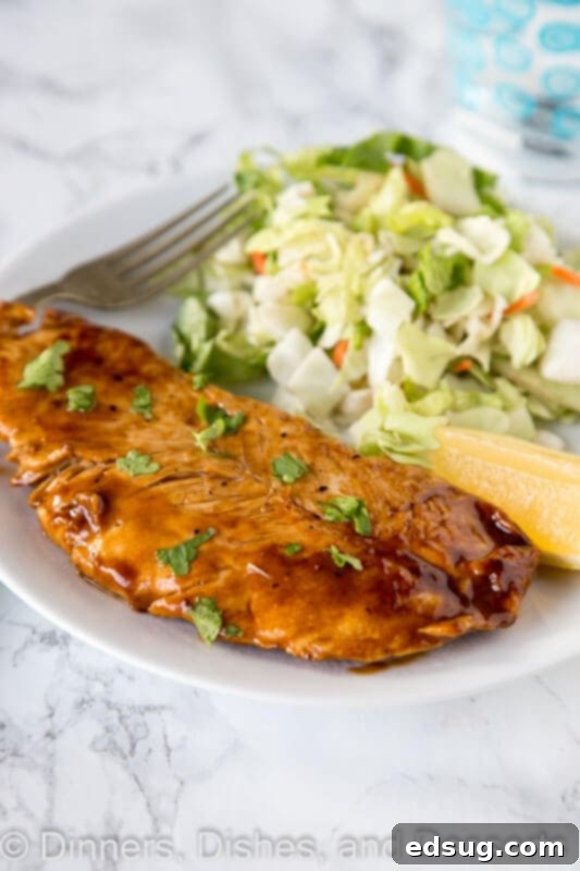 A close-up of a stack of lemon turkey cutlets with sauce drizzled over them