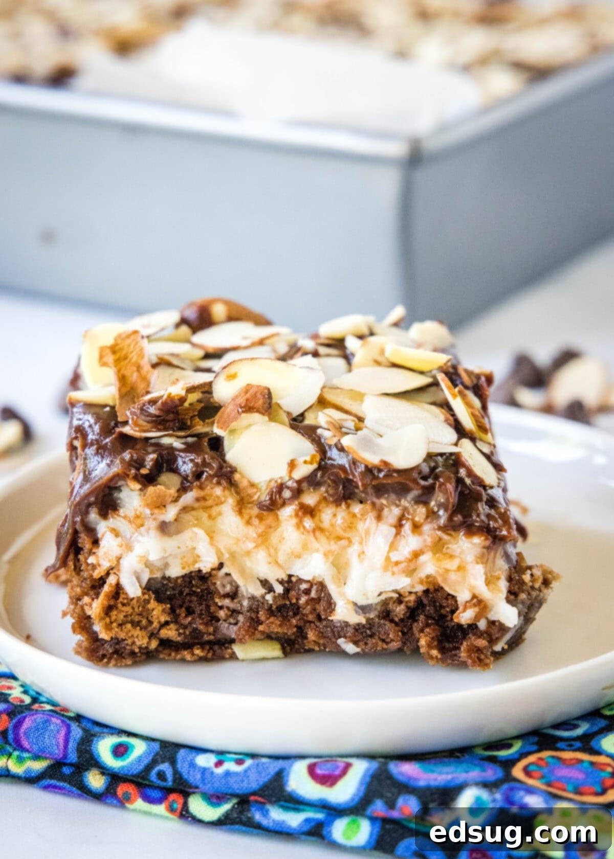 Ultimate Almond Joy Brownies 2 sliced almond joy brownie on a white plate showcasing layers