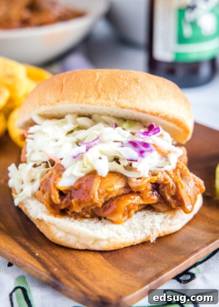 A delicious barbecue pulled pork sandwich with a side of creamy coleslaw and pickles on a rustic plate, highlighting the tender pork and vibrant colors.