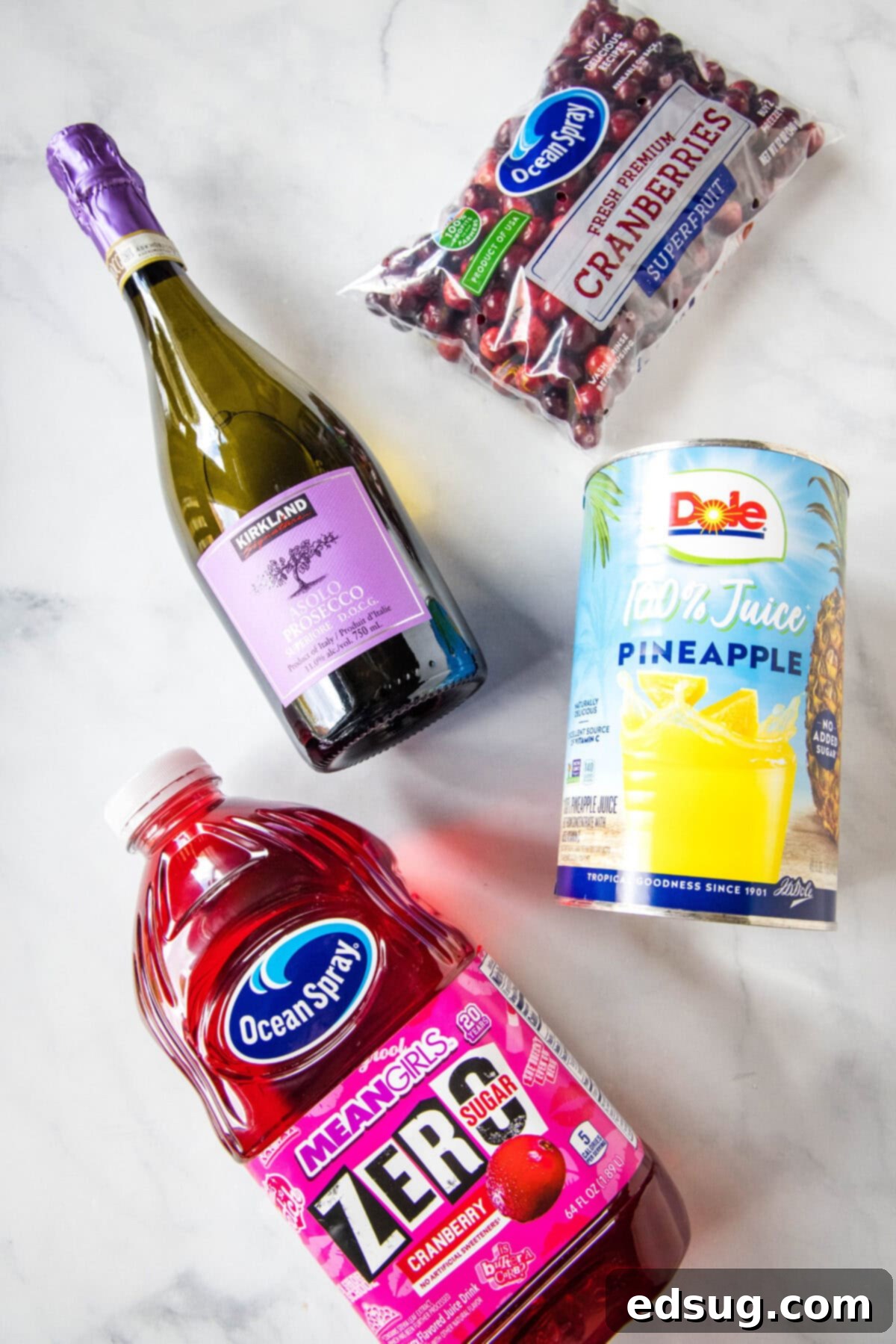 Ingredients for cranberry punch laid out: cranberry juice, pineapple juice, and sparkling wine or cider.