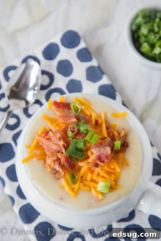 Comforting Slow Cooker Potato Soup 4 A serving of loaded crockpot potato soup, topped generously with crispy bacon, melted cheddar cheese, and chopped green onions in a white bowl.
