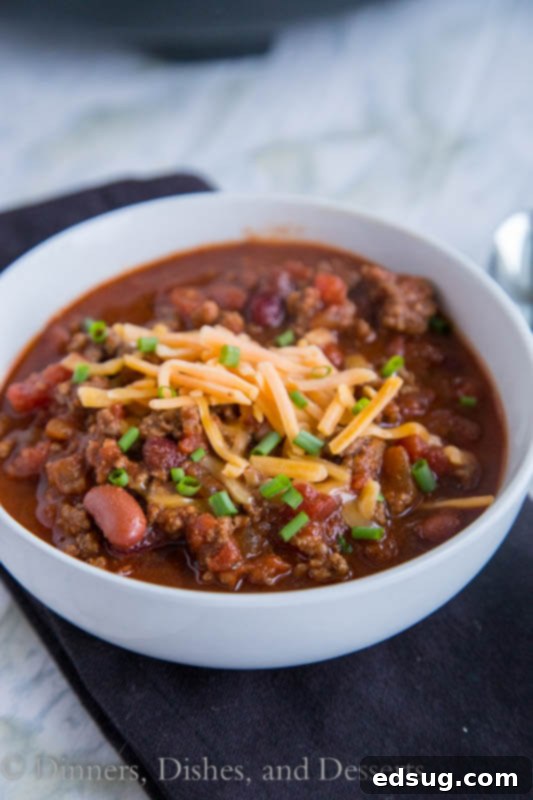 crock pot chili in a bowl, garnished with cheese and sour cream