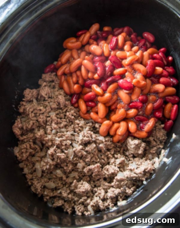 ingredients for chili in the crock pot including spices, beans, and tomatoes