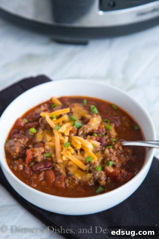 crock pot chili in a bowl with toppings and a spoon