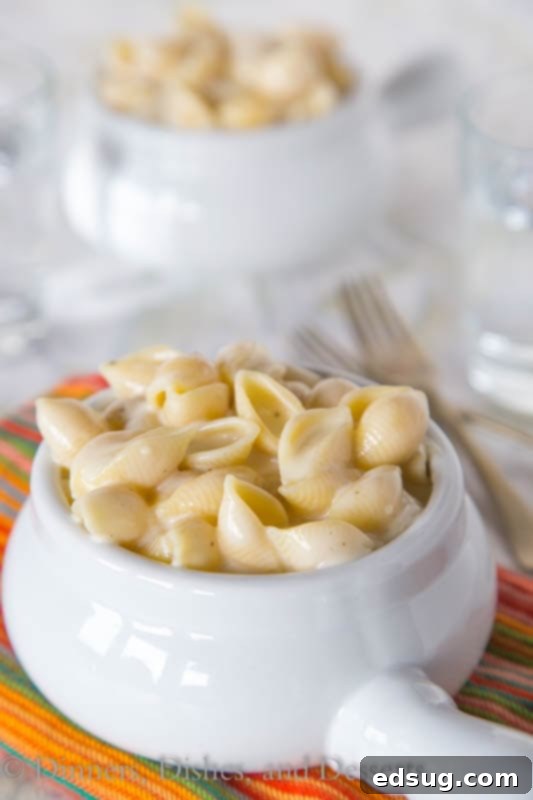 A serving of creamy Panera-style mac and cheese in a white bowl, garnished with fresh parsley.