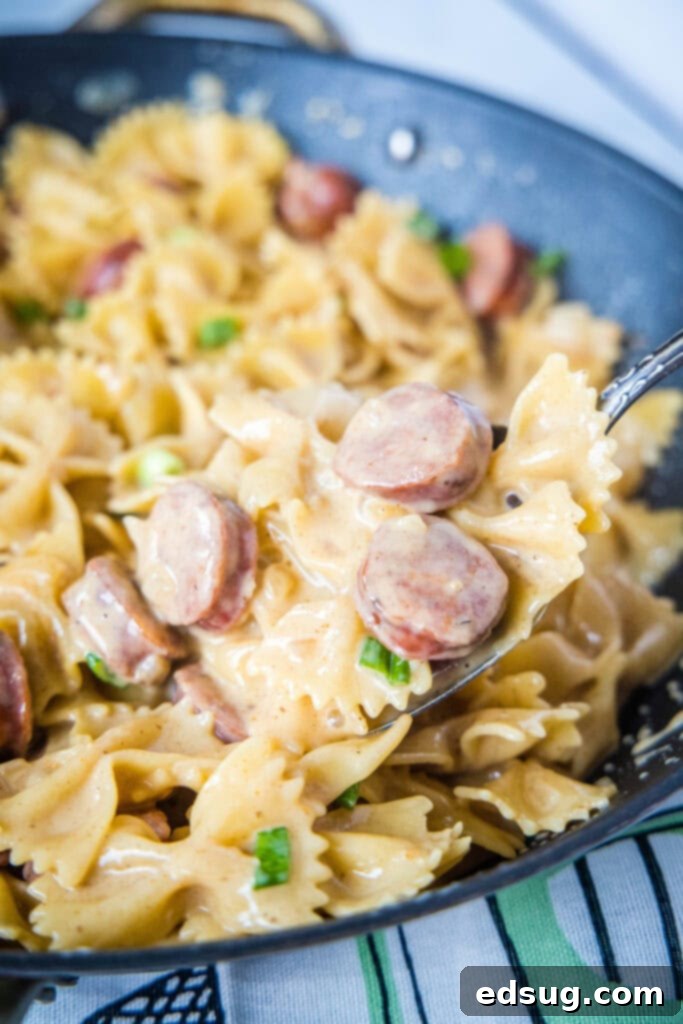 Southern Style Sausage Pasta 4 serving spoon scooping pasta out of skillet