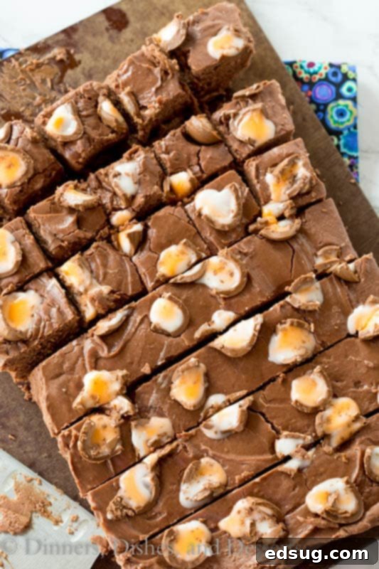 Close-up of freshly made Creme Egg Fudge slices on a wooden board, showcasing vibrant colors and chocolate pieces