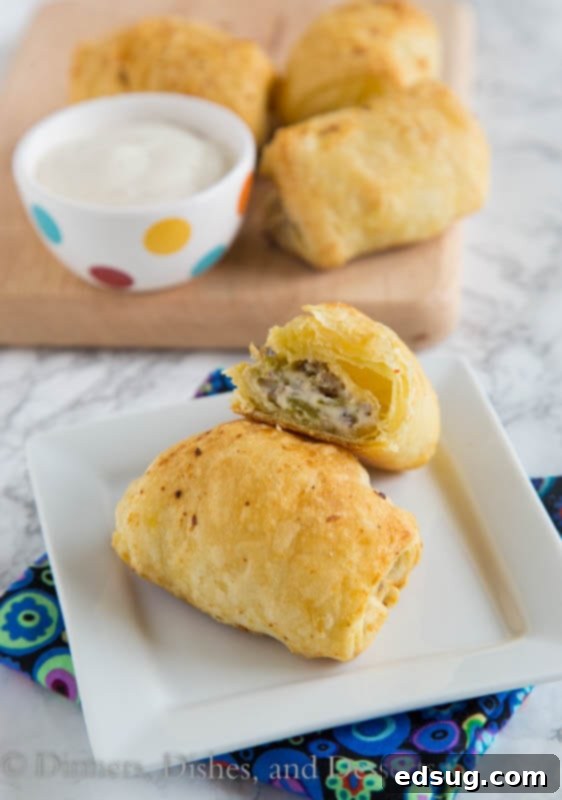 Zesty Sausage Swirls 2 Golden brown spicy sausage rolls on a white plate, garnished with fresh herbs, ready for serving