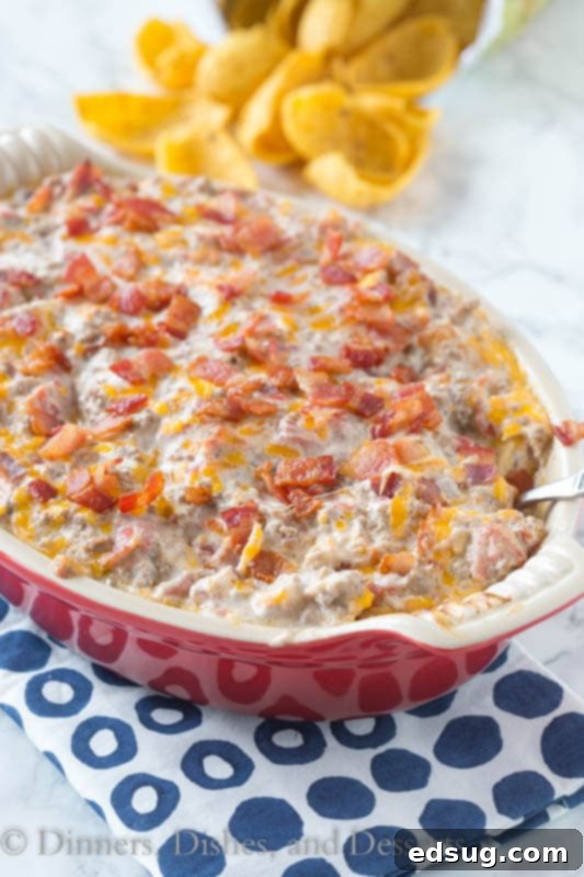 Ultimate Bacon Cheeseburger Dip 2 A close-up shot of a creamy, golden-brown Bacon Cheeseburger Dip in a baking dish, with bits of bacon and cheese visible.