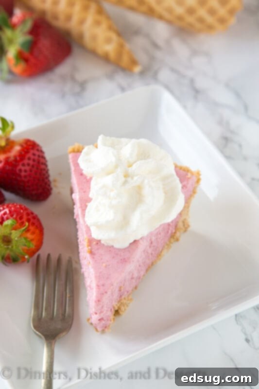 Dreamy Strawberry Milkshake Pie 4 Close-up of a slice of strawberry milkshake pie on a white plate, showing the distinct layers of waffle cone crust and strawberry filling