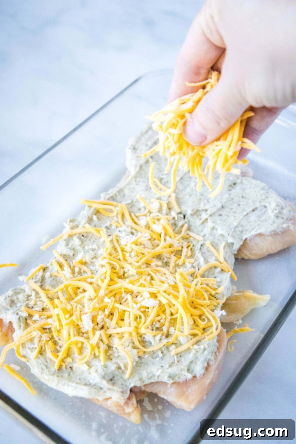 sprinkling breadcrumbs and cheese over chicken