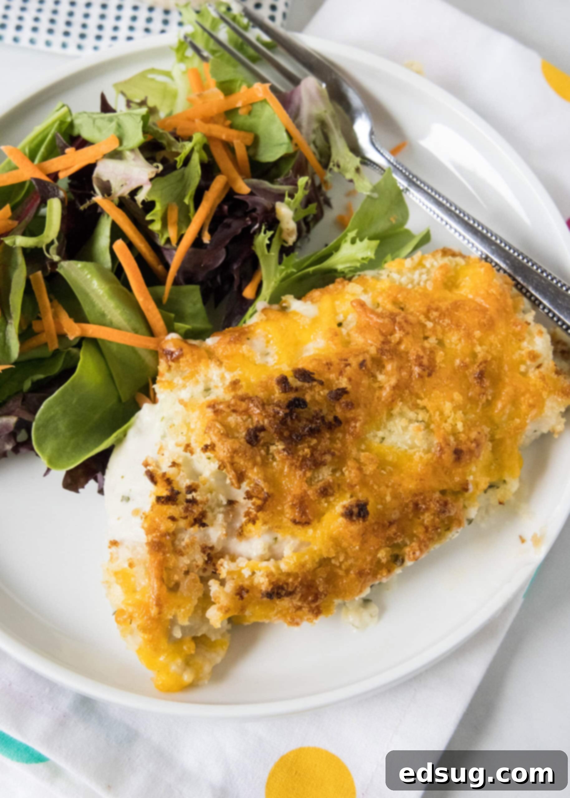 Baked ranch chicken served with a side of salad on a white plate.