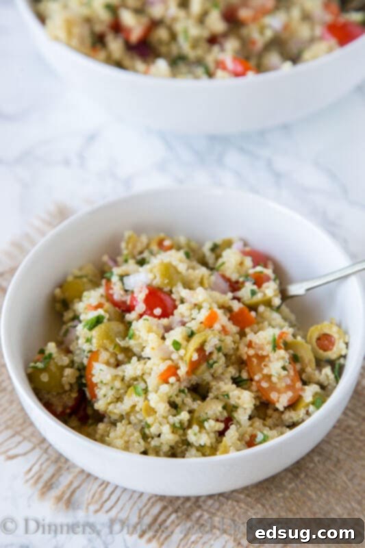 Zesty Mediterranean Quinoa Bowl 4 A serving of Mediterranean quinoa salad on a white plate with a fork, ready to be enjoyed.