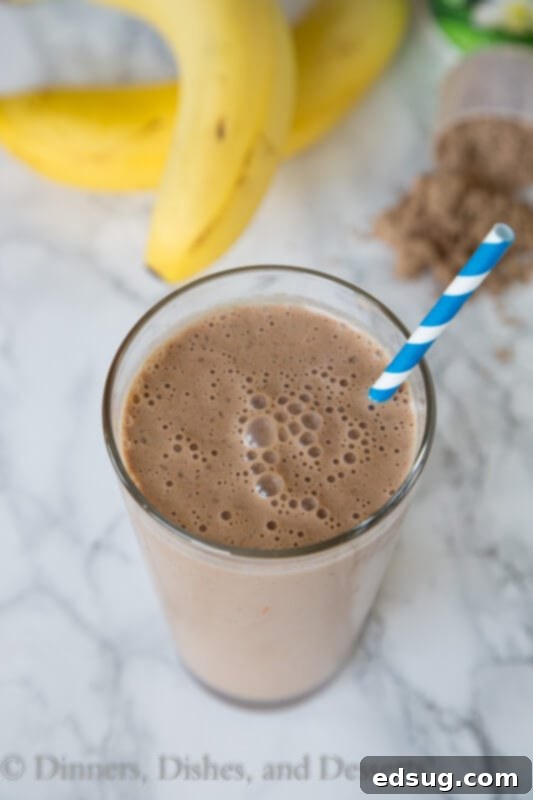 Ultimate Chocolate Peanut Butter Smoothie 2 A tall glass filled with a creamy chocolate peanut butter smoothie, topped with a straw, ready to be enjoyed.