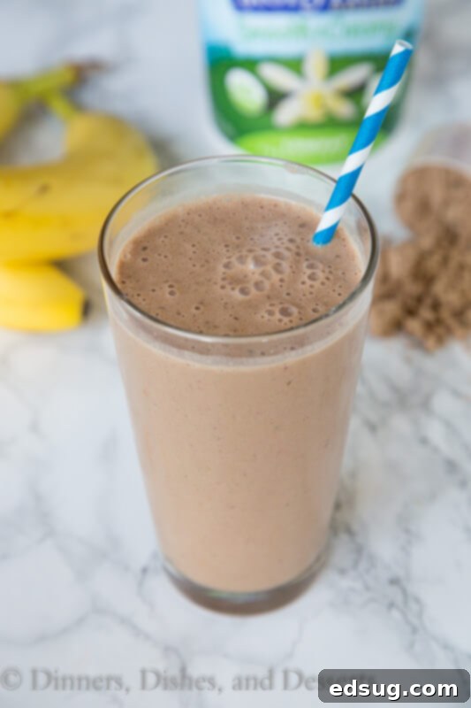 Ultimate Chocolate Peanut Butter Smoothie 4 A hand holding a glass of chocolate peanut butter smoothie, highlighting its appealing texture and rich color.