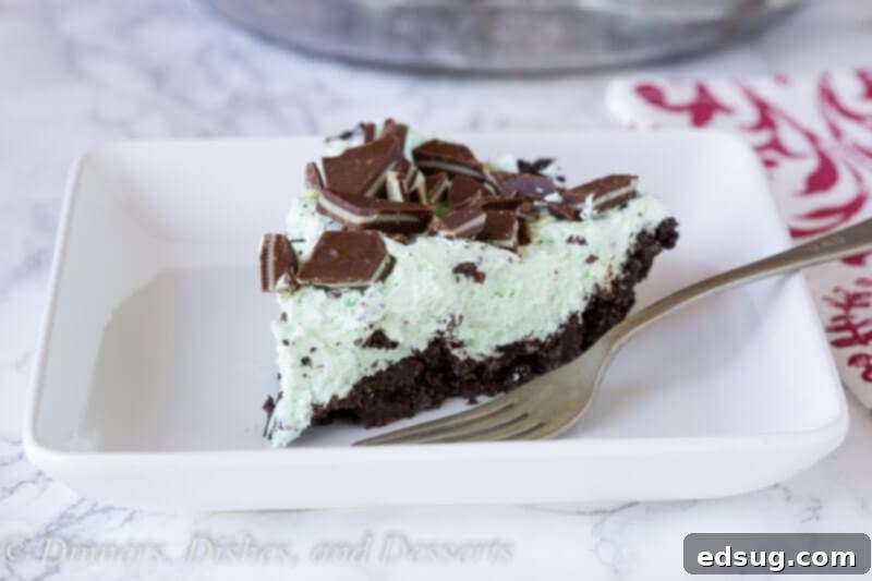 Cool Mint Chocolate Chip Dream Pie 3 No-Bake Mint Chocolate Chip Pie sliced on a plate, showing the creamy green filling and crushed mint topping