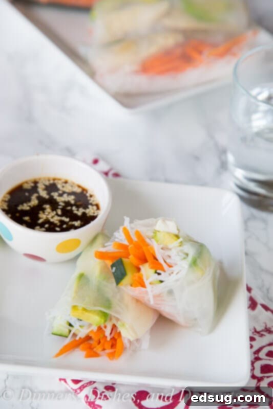 Hand preparing a chicken spring roll with fresh vegetables and rice noodles