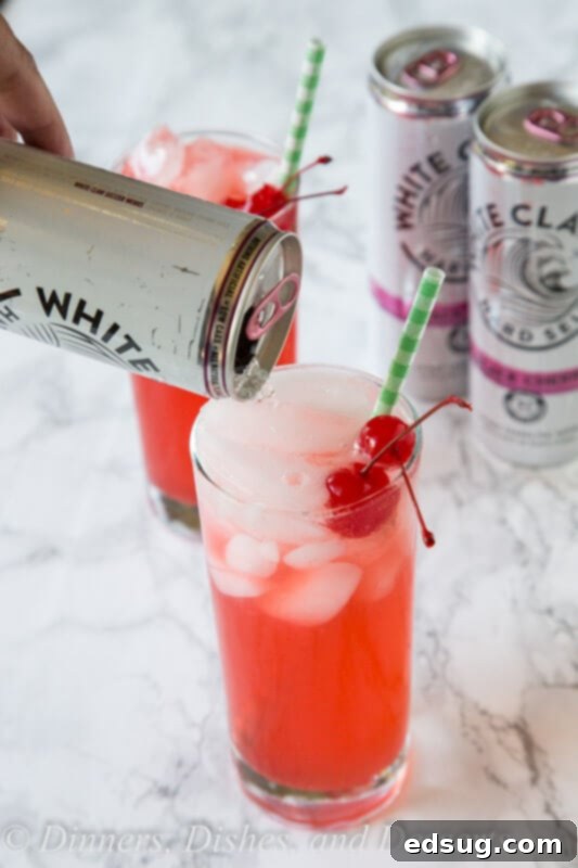 black cherry limeade cocktail in a clear glass with ice and garnishes