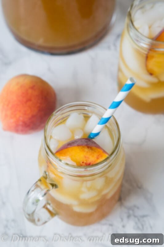 Refreshing Peach Tea Punch 4 Close-up of peach tea punch in a glass, with ice and peach slices, showcasing its inviting color and texture.