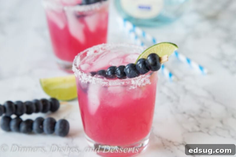 Blueberry Bliss Margaritas 3 Close-up of a blueberry margarita with mint garnish, showcasing its vibrant color and frosty rim.