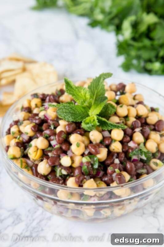 Balela Salad: Mediterranean Chickpea Medley 4 A serving of Balela salad in a white bowl with a spoon.