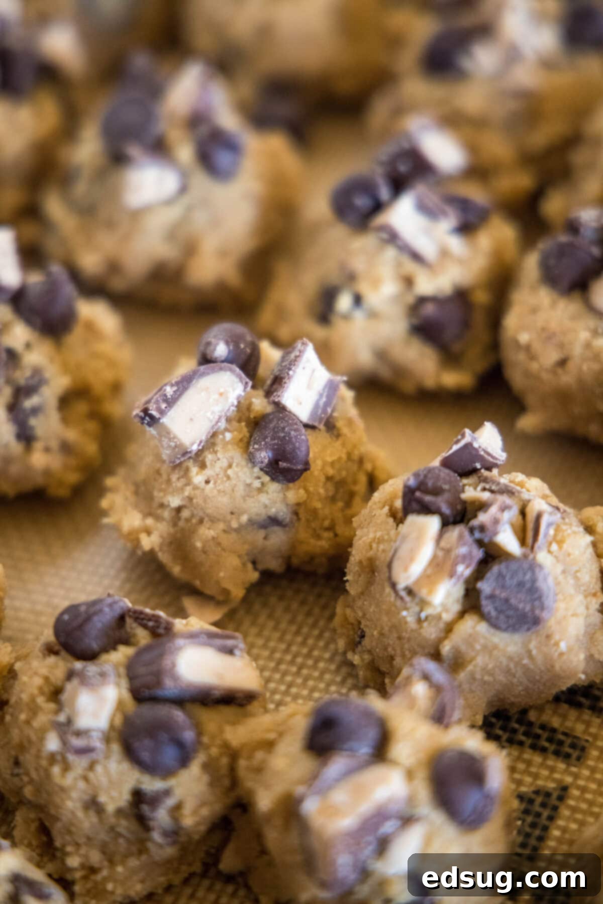 toffee graham cracker cookie dough balls topped with chocolate and toffee on a baking sheet