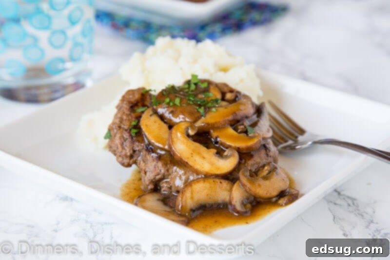 Two perfectly cooked hamburger steaks with a generous serving of mushroom gravy, ready to be enjoyed.