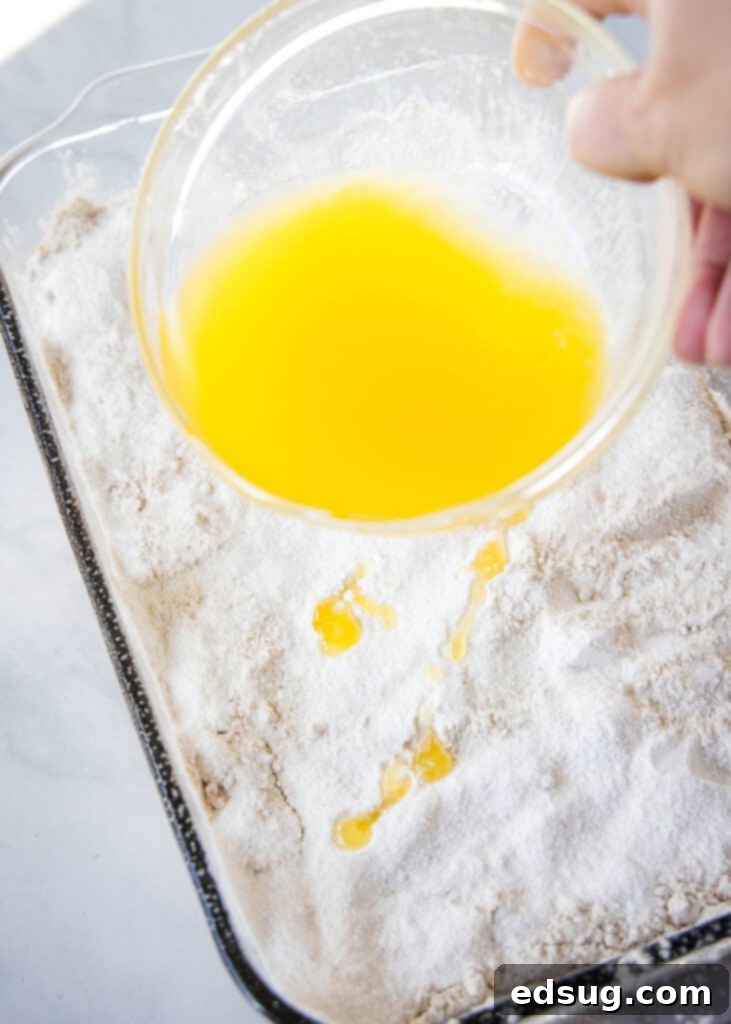 Gooey Pumpkin Crumble Delight 6 pouring melted butter over dry cake mix and pudding mix for pumpkin dump cake