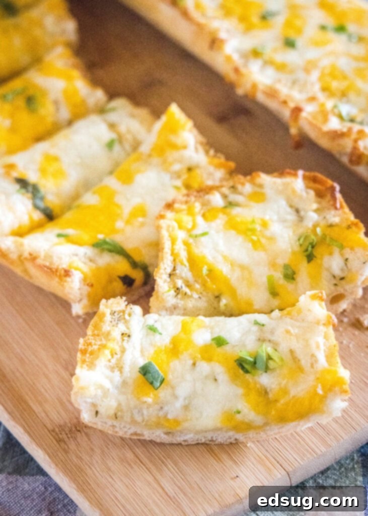 Irresistible Cheesy Garlic Bread 2 Slices of golden brown cheesy garlic bread topped with melted cheese and herbs, arranged on a wooden cutting board, ready to serve.