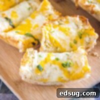 Sliced cheesy garlic bread resting on a wooden cutting board, ready for serving.