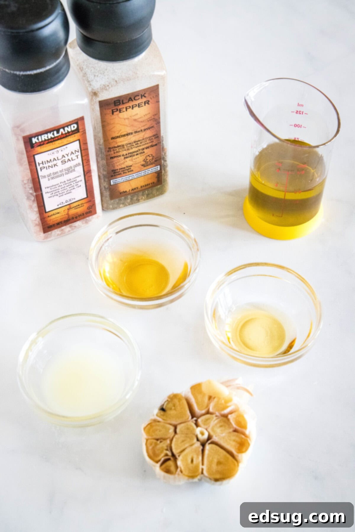 Carefully arranged ingredients for roasted garlic vinaigrette, including whole garlic heads, olive oil, and lemon