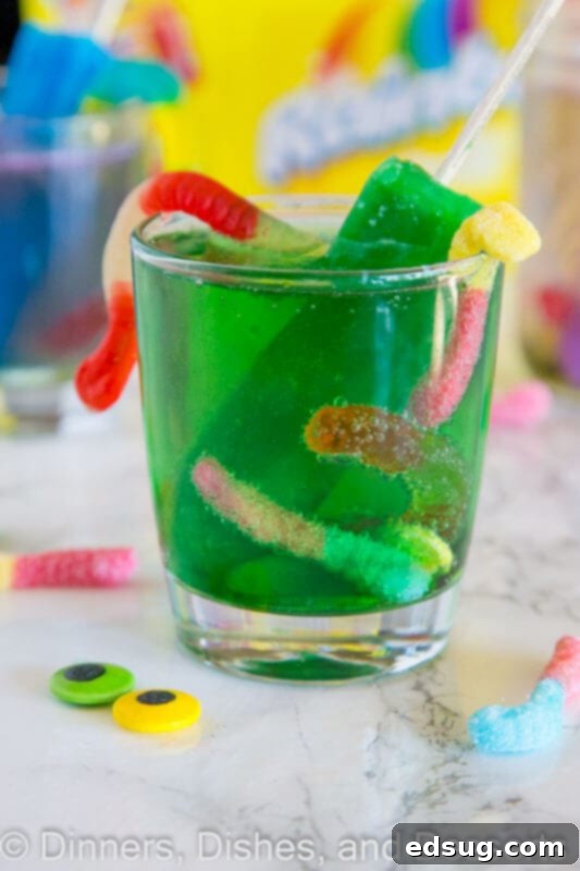 Primal Punch 2 Vibrant green monster juice in a glass, with a melting popsicle and gummy worms spilling out.