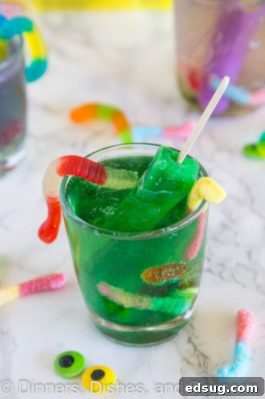 Primal Punch 4 A child's hand holding a glass of green monster juice with a melting popsicle and gummy worms.