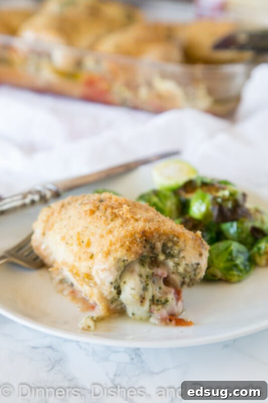 A plate featuring a perfectly baked Italian stuffed chicken breast, showing the pesto and cheese filling