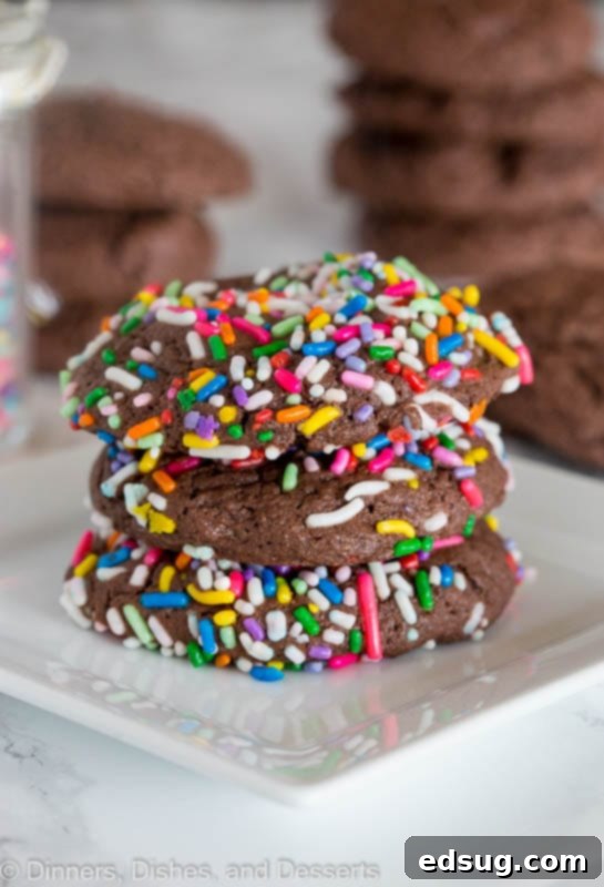 Chocolate Sprinkle Cookies - Super easy 3-ingredient chocolate cookies from cake mix that are thick, chewy, and fudgy, coated in fun sprinkles. Stacked chocolate cake mix cookies with colorful sprinkles, showing their thick and chewy texture.