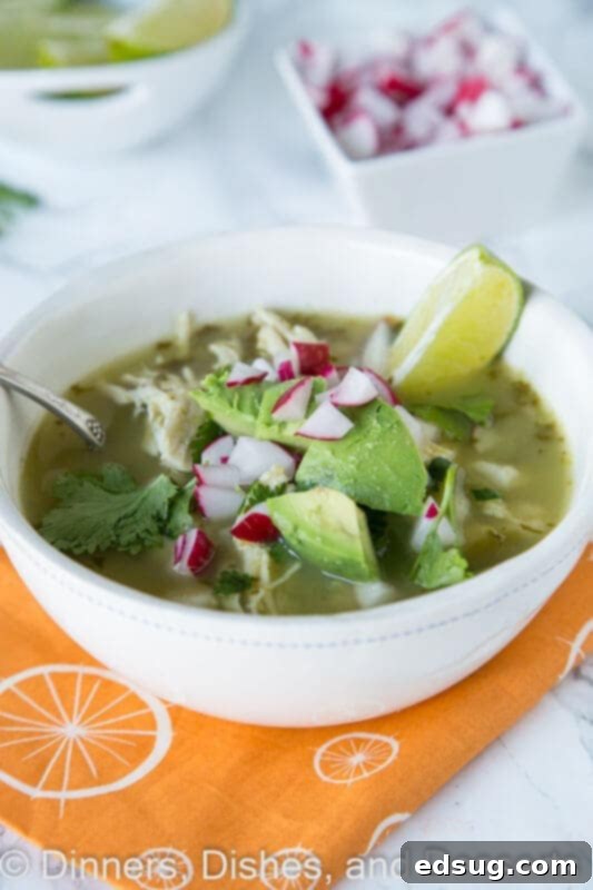 Effortless Slow Cooker Verde Chicken Pozole 2 Verde chicken pozole in a bowl, garnished with fresh ingredients