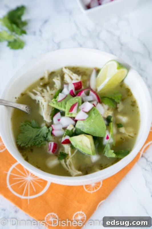 Effortless Slow Cooker Verde Chicken Pozole 4 Close-up of chicken verde pozole in a bowl, garnished