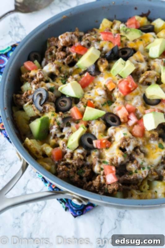 Golden brown Mexican skillet potatoes topped with taco meat, salsa, and melted cheese in a cast iron pan, ready to serve.