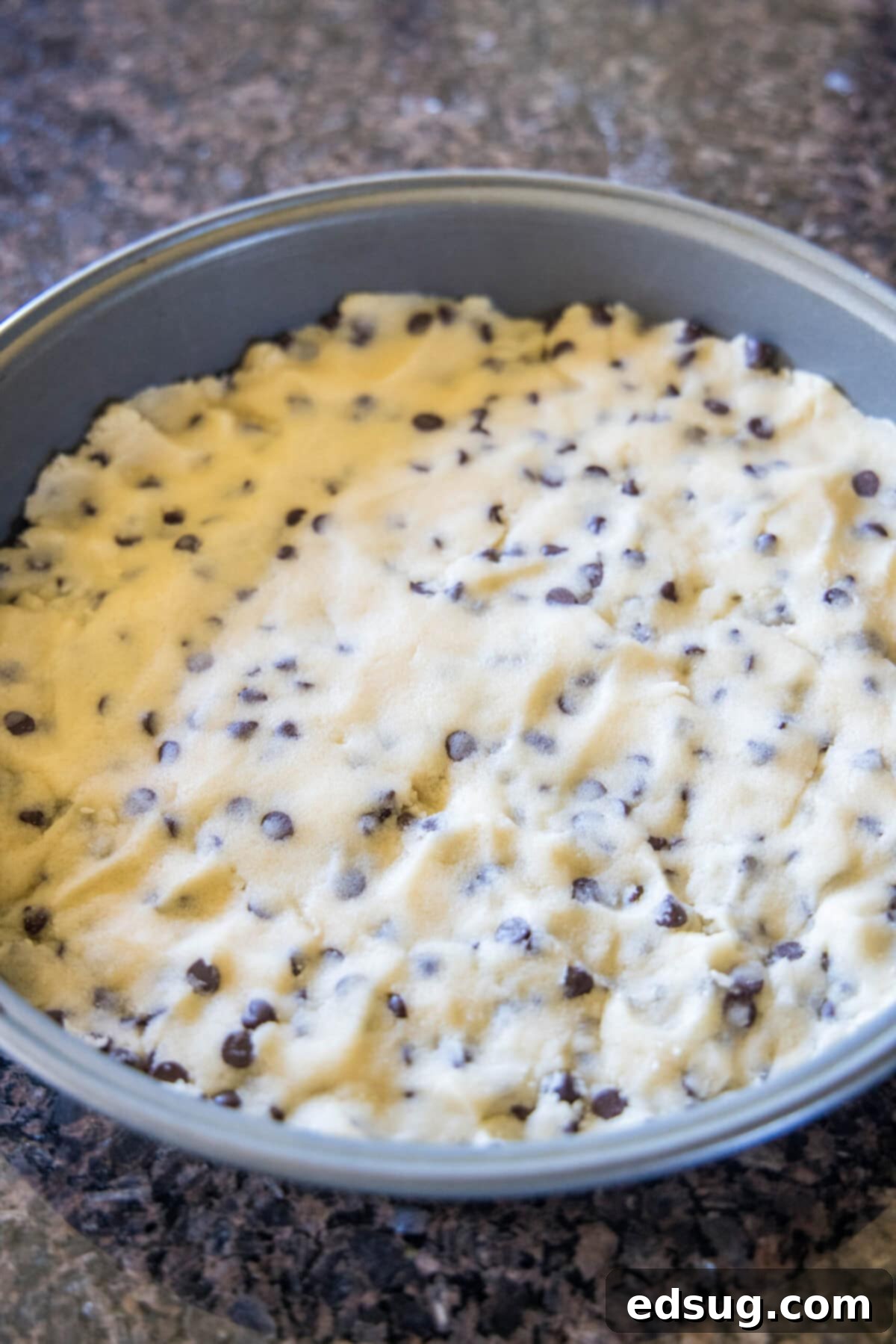 Chocolate chip shortbread dough pressed into a cake pan.