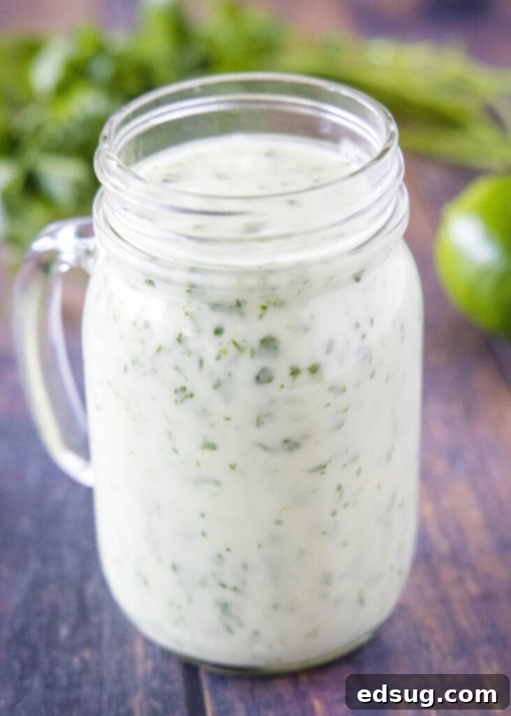 A mason jar filled with vibrant green homemade cilantro lime dressing, perfect for salads and more.