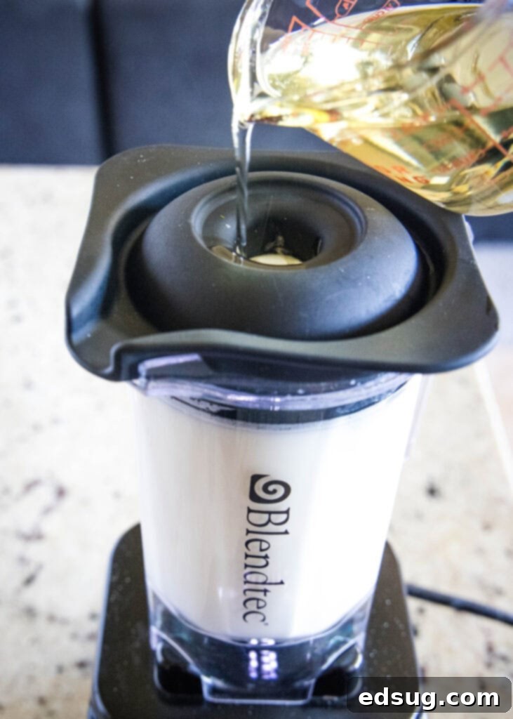 Pouring vegetable oil into a blender with other ingredients to make cilantro lime dressing.