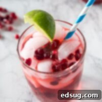 Pomegranate vodka gimlet in a cup with a straw, ready to be enjoyed.