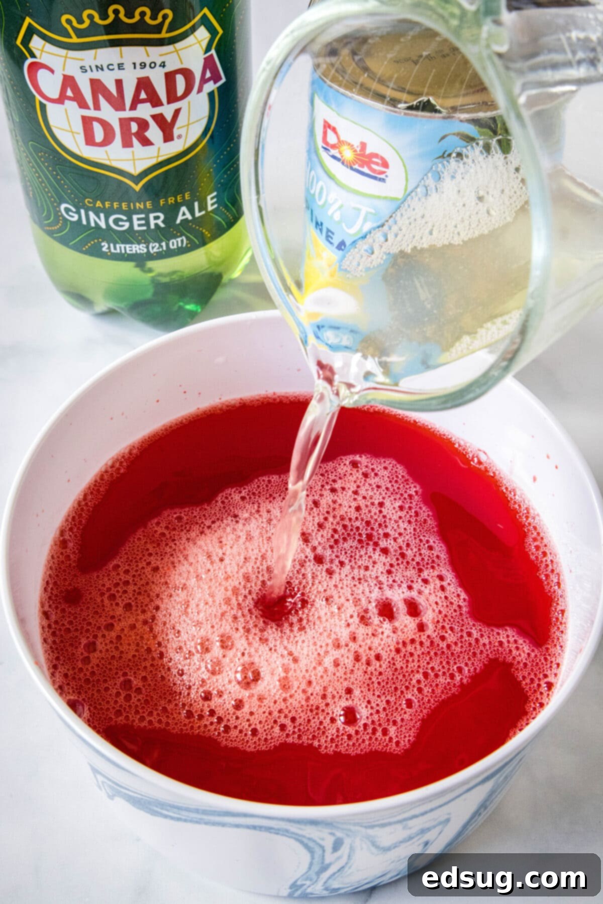 Festive Punch 5 Pineapple juice being added into a bowl of holiday punch.