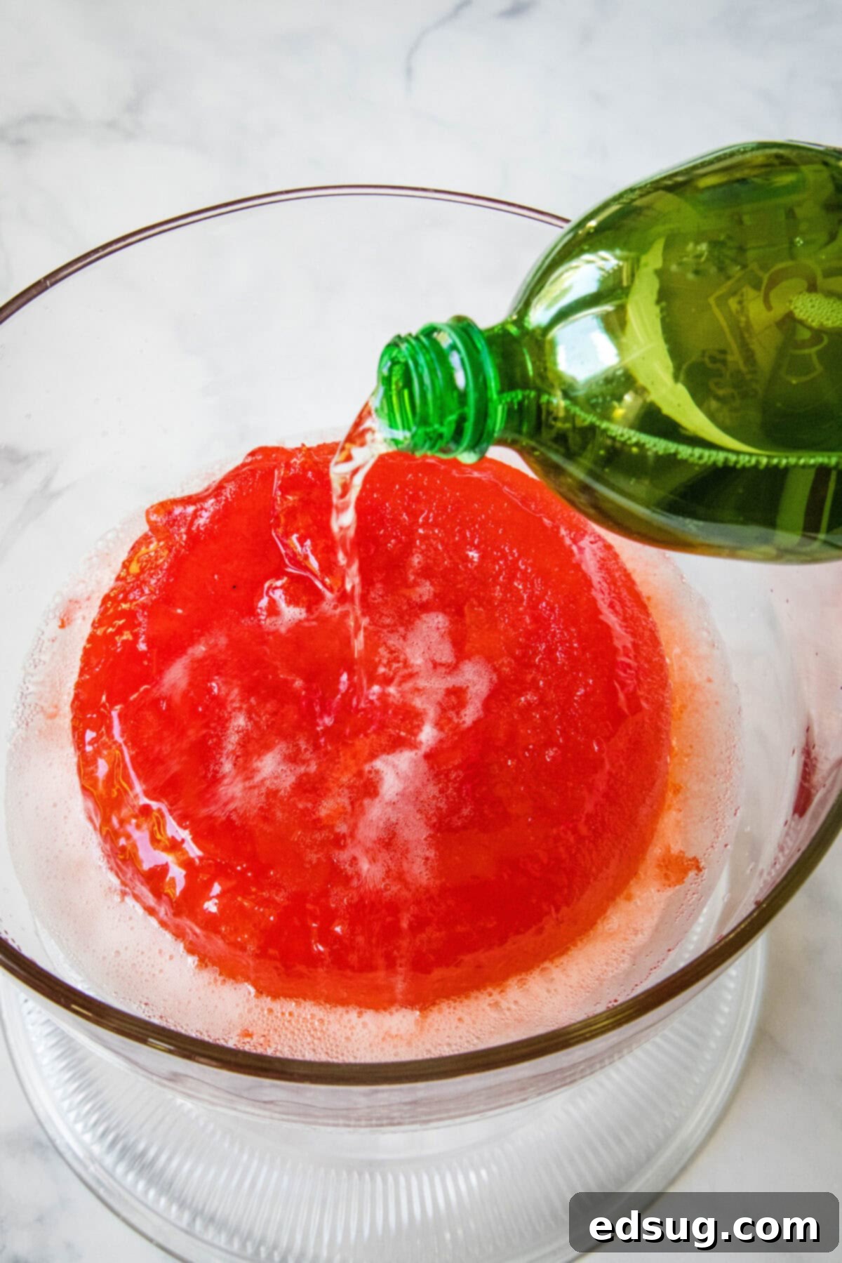Festive Punch 6 Ginger ale being poured into a large bowl of holiday punch.