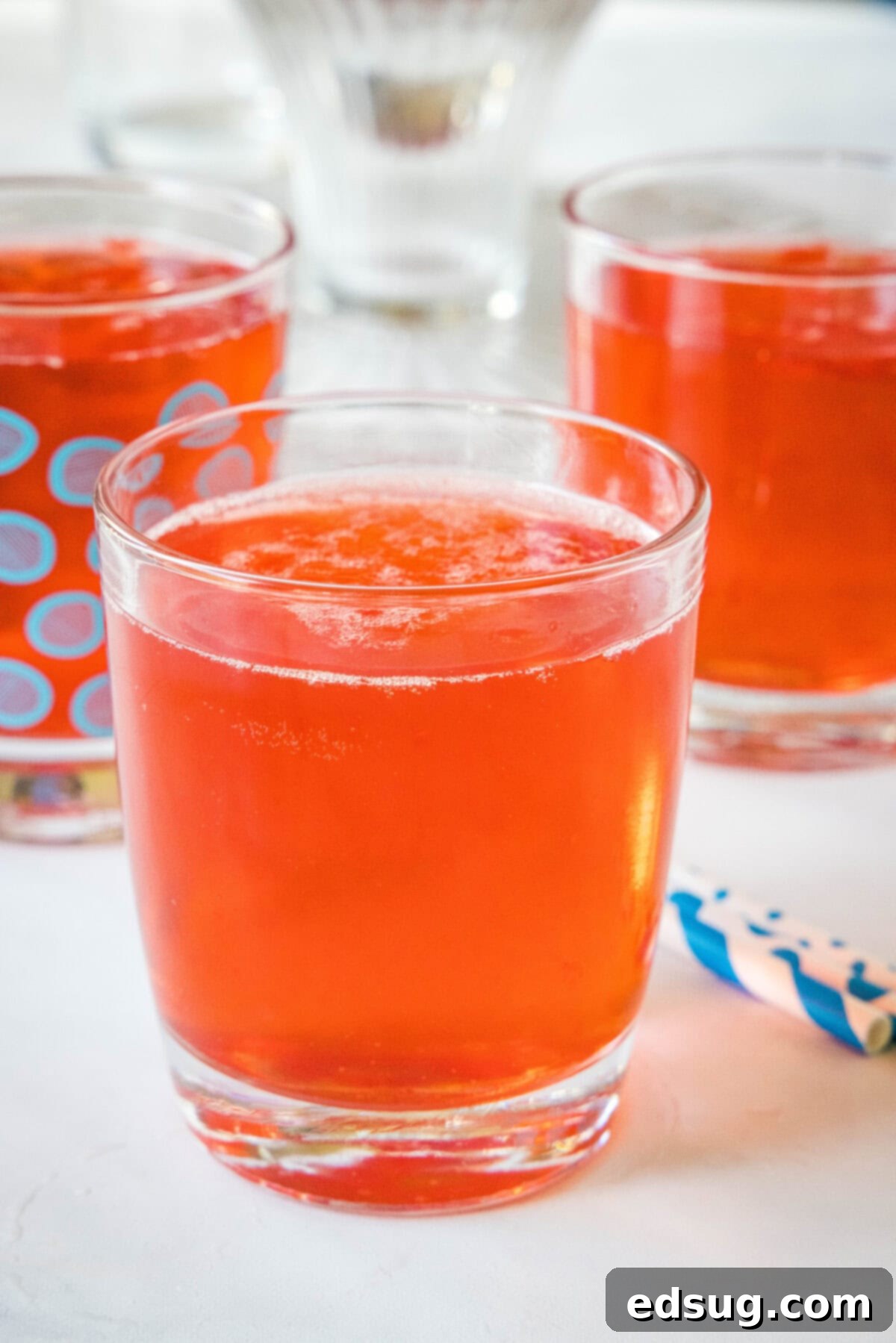 Festive Punch 7 A glass of holiday punch with more filled glasses in the background.