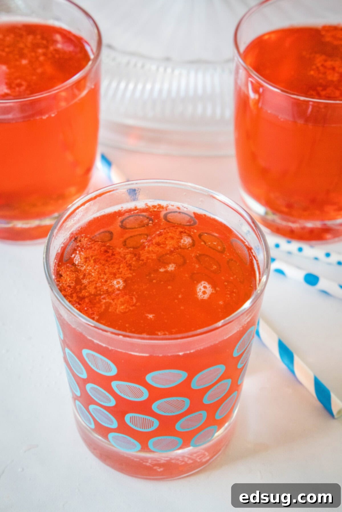 Festive Punch 8 A glass of holiday punch with more filled glasses in the background.