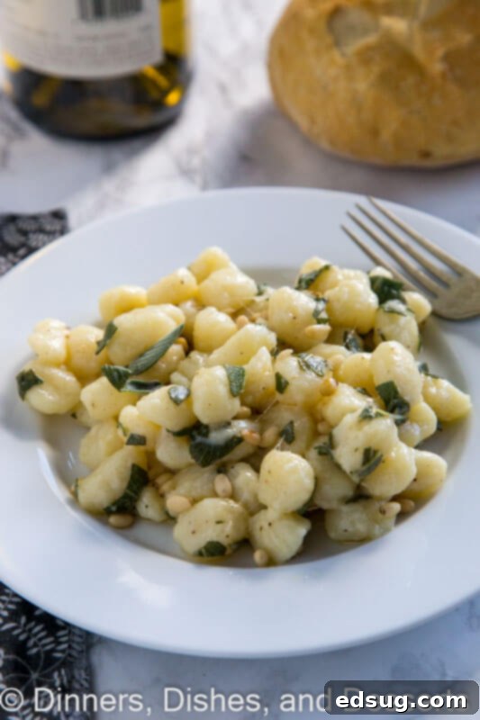 Pillowy Parmesan Gnocchi with Brown Butter Sage Sauce 2 A close-up of a plate of fluffy Parmesan gnocchi with sage butter, garnished with fresh sage leaves and a fork resting beside it.