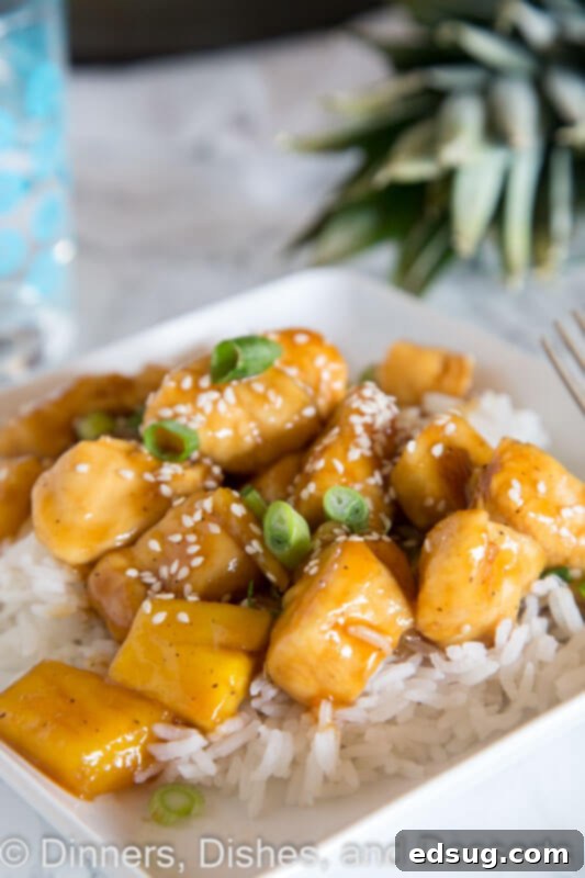 Tropical Pineapple Teriyaki Chicken 2 A plate of Pineapple Chicken Teriyaki with glistening sauce, tender chicken, and bright pineapple chunks, served over rice and garnished with sesame seeds.